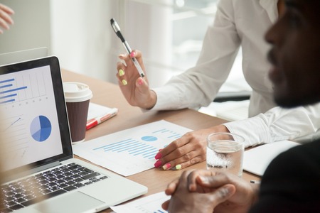 Multiracial team working together on statistics data analysis, diverse business people reviewing financial report discussing project results at meeting, brainstorming teamwork concept, close up viewの写真素材