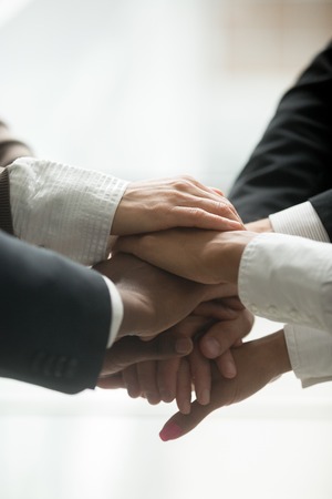 Stacked pile of hands close up vertical view, motivated multi-ethnic business team join together as...