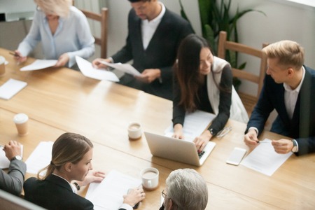 Diverse multiracial business team preparing for group meeting sitting together at conference table, multiethnic young and senior people talking discussing plans for corporate negotiations at briefingの写真素材