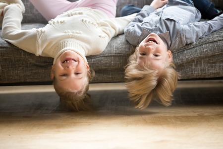 Portrait of boy and girl laughing lying upside down, happy cheerful kids brother with sister having...