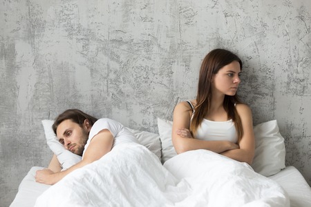 Sad millennial lovers after quarrel fight ignoring avoiding sex in bed, frustrated man and woman not talking feeling offended or stubborn, unhappy married couple and sexual problems conceptの写真素材