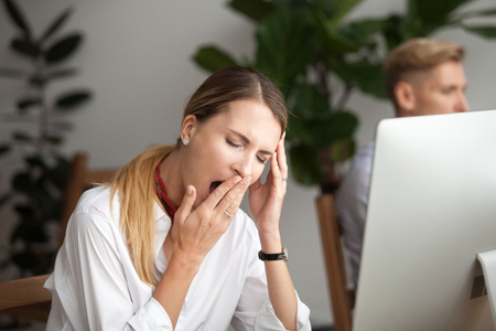 Bored businesswoman yawning at workplace feeling no motivation or lack of sleep tired of boring office routine, exhausted restless employee gaping suffering from chronic fatigue or overwork conceptの写真素材