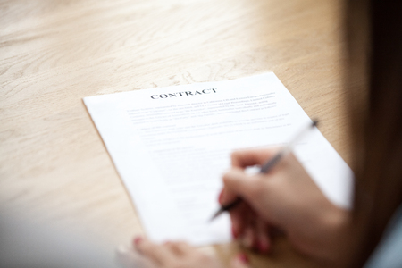Female hand putting signature on business contract, woman client agreeing on terms making sale purchase deal signing legal paper, mortgage, insurance, loan or employment concept, focus on documentの写真素材