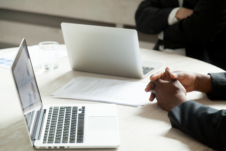 Close up of multiethnic work briefing, managers working with financial diagrams on laptops. Concept of coworking, brainstorming and diversity. Round table board meeting, african american team memberの写真素材