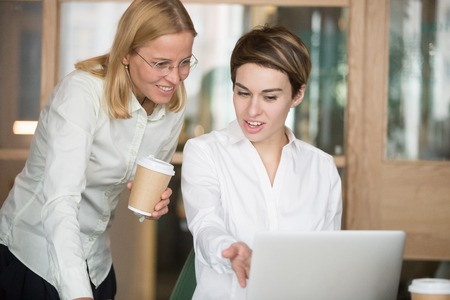 Two smiling businesswomen discussing good online project result or achievementの写真素材