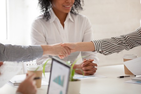 Businessman and businesswoman handshaking at diverse group meeting or negotiations, close up view of female and male hands shaking as concept of making financial deal and new project partnershipの写真素材