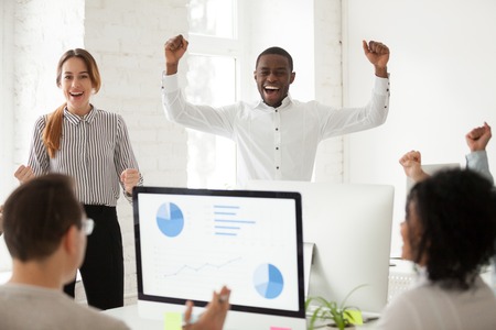 Ecstatic multiracial team excited by good news in online project report celebrating win amazing business victory together, african and caucasian corporate colleagues happy with great work resultsの写真素材