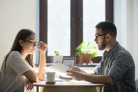 Concerned millennial business workers discussing contract, confused man expressing his thoughts, female listening attentively. Employees negotiating over deal or agreement. Concept of work disputeの写真素材