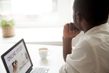 Thoughtful black student looking in window being distracted from work, not performing education learning online course, thinking about future achievement and success. Laziness, motivation lackの写真素材