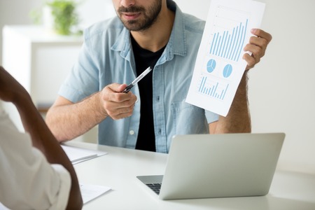 Close up of financial manager showing visual template to colleague, explaining growing rates on diagrams and graphs, talking about company strategy, presenting project. Concept of coaching, leadershipの写真素材