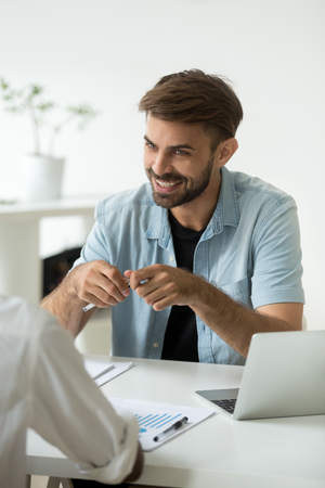 Smiling Caucasian worker laughing while talking to colleague in office, negotiating about work issues, discussing business project, financial rates and growing sales. Cooperation, teamwork conceptの写真素材