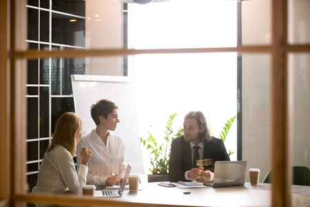3 smiling business colleagues having casual conversation in boardroom, businessman talking, sharing thoughts with businesswomenの写真素材
