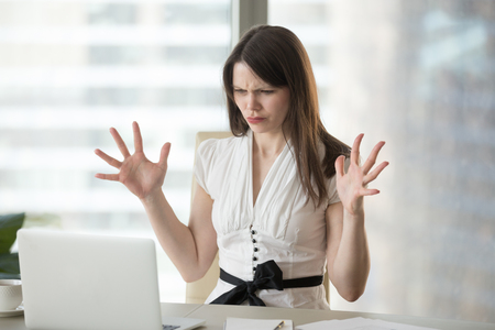Frustrated female worker having software problems with laptop, angry woman get nervous seeing error or mistake notification at computer screen, mad employee experience virus attack or app malfunctionの写真素材