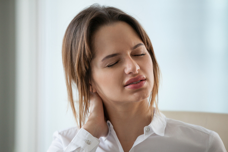 Close up of exhausted millennial female worker massage neck, suffering from muscle pain working long hours in incorrect posture, tired businesswoman relieve discomfort from sedentary lifestyleの写真素材