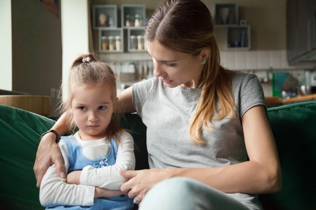 Loving mother consoling or trying make peace with insulted upset stubborn kid daughter avoiding talk, sad sulky resentful girl pouting ignoring caring mom embracing showing support to offended childの写真素材