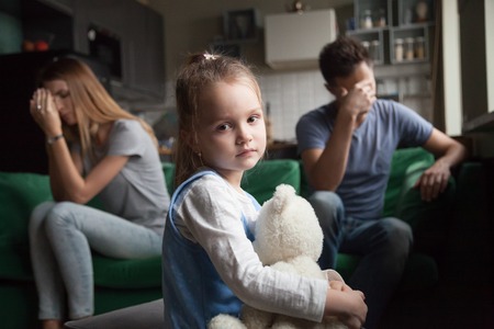 Frustrated little girl upset tired of parents fight looking at camera, portrait of sad preschool kid daughter suffers from family mom and dad arguments or lack of attention, child and divorce conceptの写真素材