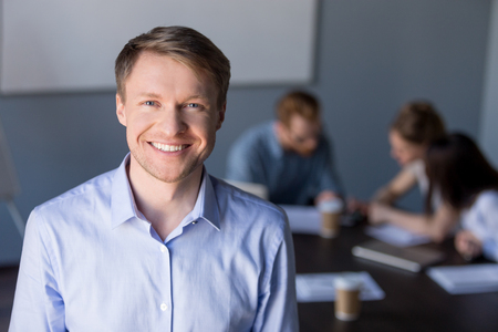 Portrait of smiling middle-aged male employee posing during company team meeting in boardroom, confident happy businessman looking in camera, making picture for corporate catalogue during briefingの写真素材