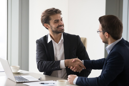 Happy business partners shaking hands after successful negotiations in office, company CEO handshake colleagues thanking for meeting, businessmen handshaking closing deal. Cooperation, interview, hrの写真素材