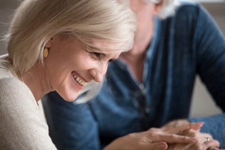 Happy middle aged senior woman with beautiful face laughing flirting with beloved older man, smiling loving wife enjoying humor talk with elderly husband, mature family couple having fun on dateの写真素材