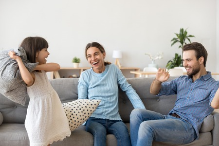 Multi-ethnic diverse family have fun in living room at home. Little daughter enjoy weekend playing...