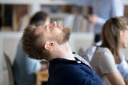 Tired male employee throw head back relaxing taking nap at workplace, exhausted worker falling asleep in office chair, man having break feeling fatigue from too long working at computerの写真素材