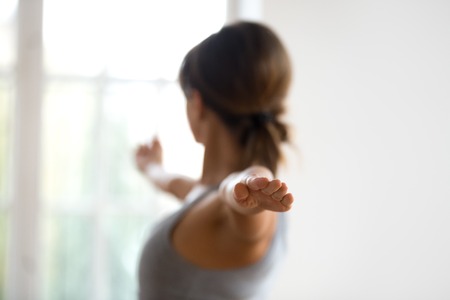 Young sporty attractive woman practicing yoga, doing Warrior II exercise, Virabhadrasana 2 pose,...