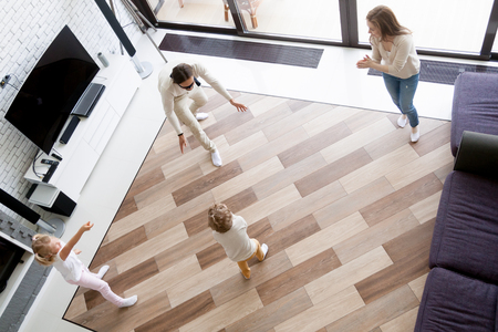 Happy funny family with little preschool son and daughter spending free time together on weekend at new modern home. Playful dad with covered eyes playing hide and seek in living room, top above view.の写真素材