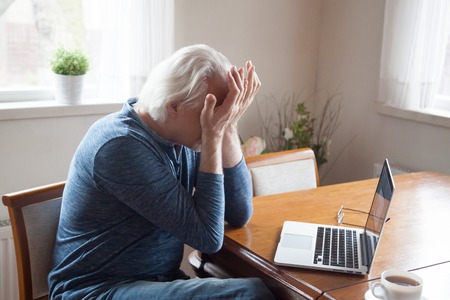 Tired aged man massaging eyes working too long at laptop, senior male feel exhausted suffer from headache after using computer, elderly having blurry vision or dizziness from pc screenの写真素材