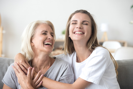 Happy senior mature mother embracing young adult woman laughing together, smiling elderly older mum joking having fun with grown daughter, two age generations humor and positive emotions conceptの販売画像