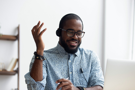 Black millennial cheerful student learn foreign language via internet using computer and headphones make video call talking with teacher online. Education, e-learning and modern technologies conceptの写真素材