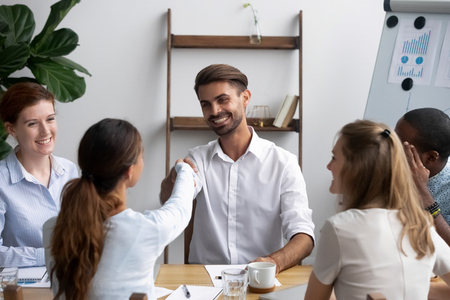 Successful businesspeople gathered together in office boardroom for negotiate and discuss new project greeting shaking hands. Company executive manager welcoming newcomer new worker female handshakingの写真素材