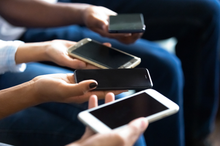 Multiethnic people holding phones in hands screen up mock up, using mobile devices, browsing apps, smartphones, social network, technology addiction, dependence, hands view close upの写真素材