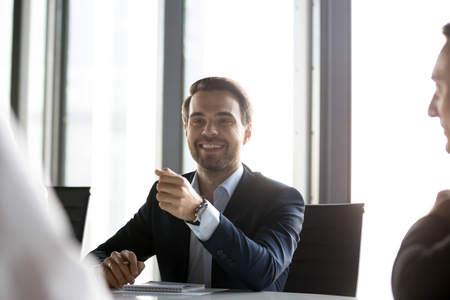Corporate business team gathered in modern office boardroom discussing planning brainstorming together focus on positive successful businessman company owner sitting at desk communicating with staffの写真素材