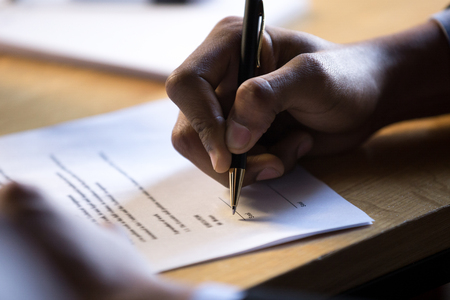 Male african hand signing financial contract concept, black businessman put write signature on legal corporate paper fill document form buy insurance loan, making business agreement, close up viewの写真素材