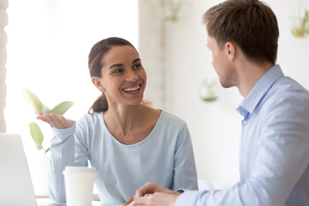Smiling woman talking with colleague during break at workplace, happy female worker share thoughts, discussing new idea, having fun together, pleasant conversation with businessman, clientの写真素材
