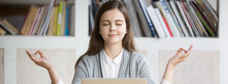 Horizontal photo businesswoman employee student meditating sitting near laptop at workplace, stress relief during workday office yoga concept, banner for website header design with copy space for textの写真素材