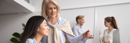 Horizontal photo aged boss mentor helping young asian intern with software, diverse people using...