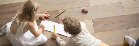 Horizontal top above photo little children preschool brother sister drawing on warm wooden floor play spend free time at modern home together, banner for website header design with copy space for textの写真素材