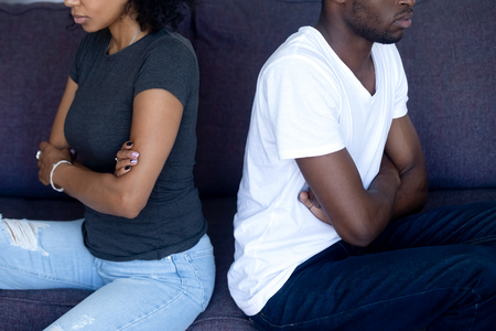 Unhappy stubborn african couple sit on couch turn back ignoring each other after fight, black upset spouses not talking having disagreement, bad relationships, misunderstandings, selfishness conceptの写真素材
