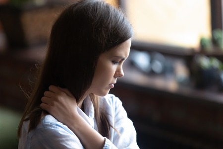 Close up face of young sad woman sitting alone feels lonely thinking about unrequited love has difficulties in relations with beloved one. Parent and teen misunderstandings teenagers problem conceptの写真素材