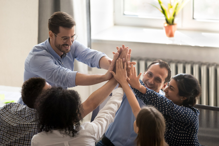 Successful millennial coworkers rises hands giving high five congratulating each other with great...