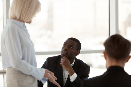 Multi-ethnic businesspeople communicating discussing planning startup business plan during meeting negotiations in office boardroom, focus on black african male. Workers listens coach sharing ideasの写真素材
