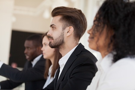 Side view diverse businessmen businesswomen headed by company president sitting at business meeting or job interview, close up focus on confident team leader. Partnership and human resources conceptの写真素材