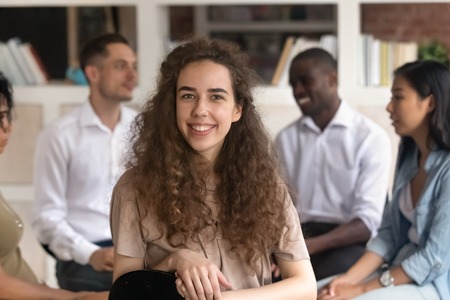 Young female therapist, training participant patient coach looking at camera at group therapy, woman...