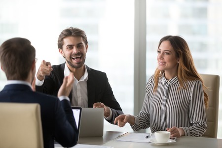 Cheerful colleagues laughing at joke at meeting, happy executives having fun tell humorous story having pleasant funny conversation in office, positive businesspeople burst with laughter at meetingの写真素材