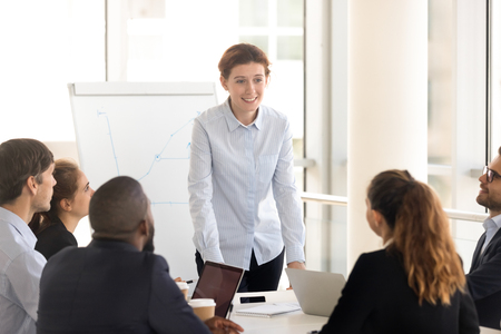 Attentive multinational people brainstorming sitting around desk in briefing at boardroom, multiracial employees listening company executive manager or business trainer, coaching and mentoring conceptの写真素材