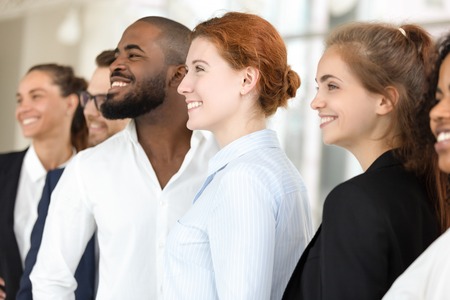 Cheerful multi-ethnic millennial professionals company members, young employees looking away standing in row, motivated staff business people posing together, workforce and sales team portrait conceptの写真素材