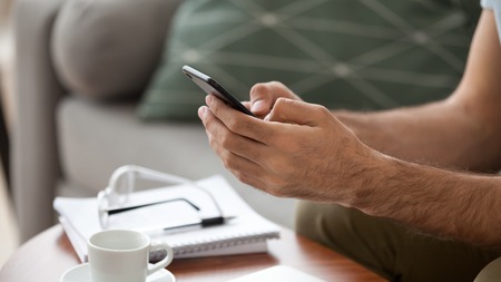 Close up man using, holding phone in hands, typing message in social network or messenger, browsing...