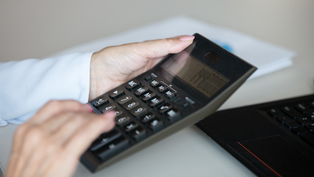 Businesswoman professional holding using office calculator for business financial accounting, female accountant bookkeeper check budget calculate money bills finances expenses concept, close up viewの写真素材