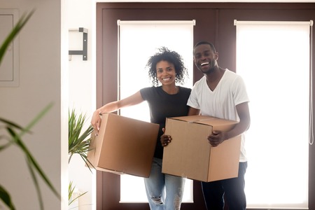 Portrait happy African American couple on moving day in new house, smiling black man and woman...